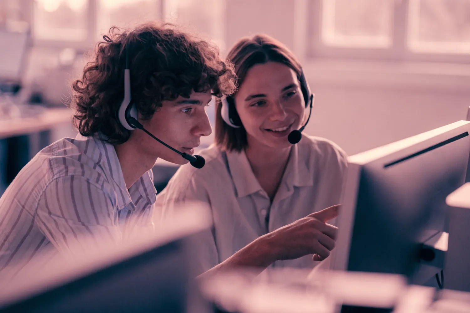 Two Digital Surge support agents wearing headsets, helping a customer at a screen